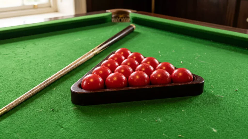 Snookerkeu en driehoek met rode ballen liggen klaar op het groene laken
