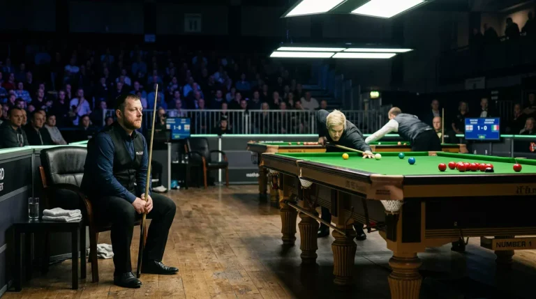 Snookerspeler kijkt toe vanaf zijn stoel terwijl de tegenstander aan de tafel speelt